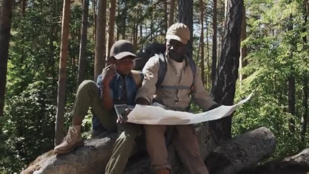 Afroamerykanin Senior Jego Wnuk Plecakach Siedzący Skale Górzystym Lesie Letni — Wideo stockowe