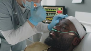 Kafasından yaralanan Afrikalı Amerikalı bir hastanın maske takan kadın doktorunun seçici odak noktası.