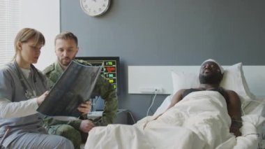 Askeri hastanede çalışan doktor, hastaların röntgen görüntülerini diğer askerlere gösteriyor.