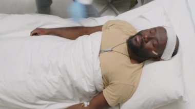 Kafasında kurşunla acı çeken Afrikalı Amerikalı askerin yukarıdan bakıldığında, doktor onun için acil durum prosedürleri uyguluyor.