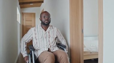 Kameraya doğru tekerlekli sandalyede giden Afrikalı Amerikalı bir adam.