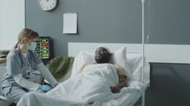 Askeri hastanede çalışan beyaz kadın bir doktor hastasının önünde oturup onunla tedavi hakkında konuşuyor ve tavsiyelerde bulunuyor.