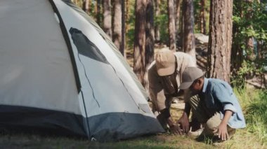 Afrikalı Amerikalı büyükbaba ve torun çadırı kurmayı bitirdikten sonra kazığı yere çakıp içeri girdiler.