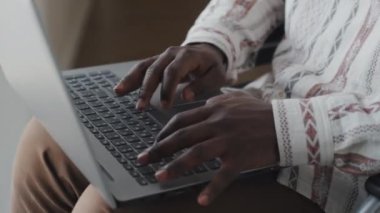 Afro-Amerikan gözlüklü bir adamın laptopta yazarken görüntüsü kesilmiş. Muhtemelen çalışıyor.