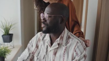 Tekerlekli sandalyedeki Afrikalı Amerikalı adamın genç beyaz bir kadınla el ele tutuşup flört etmesi.
