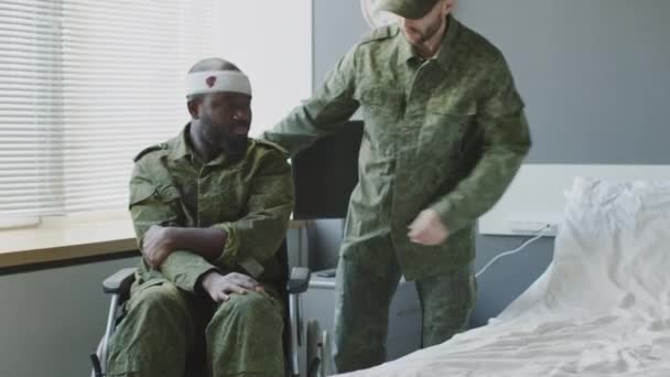 Teniente Caucásico Ayudando Amigo Negro Herido Acostarse Habitación Del Hospital — Vídeos de Stock