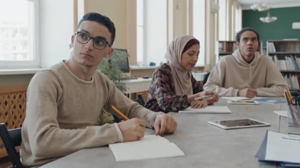 Этнически Разнообразные Студенты Иммигранты Сидят Столом Библиотеке Делают Заметки Время — стоковое видео