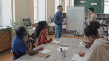 Çok ırklı göçmen öğrenciler eğitim merkezinde ders sırasında İngilizce düzensiz fiiller öğreniyorlar