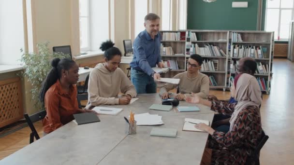 Englischlehrer Arbeitet Bildungszentrum Für Immigranten Und Verteilt Papiere Mit Grammatiktest — Stockvideo