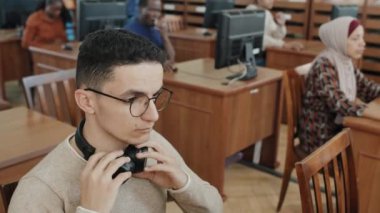 Ortadoğulu genç öğrencilerin seçici odak portresi. Kulaklık takarak dinleme işi yapıyor.
