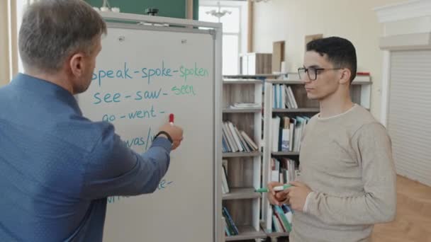 中东年轻人参加移民英语课 在白板上书写过去分词形式的不规则动词 — 图库视频影像