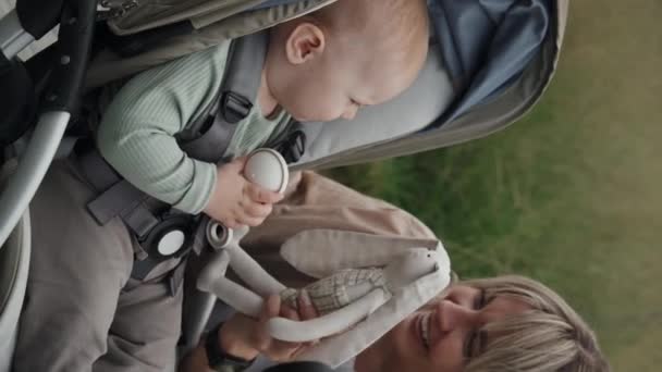 彼に玩具ウサギを示す彼女の赤ちゃんと遊ぶ若い母親の垂直ショット — ストック動画