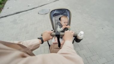 Bebek arabasındaki bebekle dışarıda yürüyen tanınmayan bir kadının yüksek açılı görüntüsü.