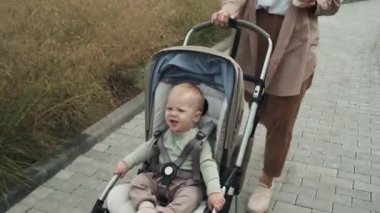 Yavrusuyla bebek arabasında yürürken günlük giysiler giymiş, temiz su içen beyaz bir kadının fotoğrafını çekiyorum.