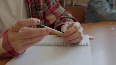 Ders ya da konferans sırasında dönen ve dönen kalemle tanınmayan kız öğrencinin yakın çekim görüntüleri.