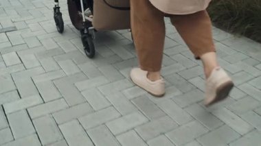 Yavaş çekim. Bebek arabalı, bebek arabalı, tanınmayan bir kadının görüntüsü.