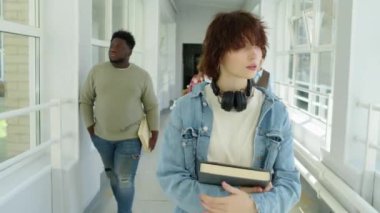 Z jenerasyonunda şık giyinen, kulaklık takan, kolej koridorunda yürürken çekilmiş bir fotoğraf.