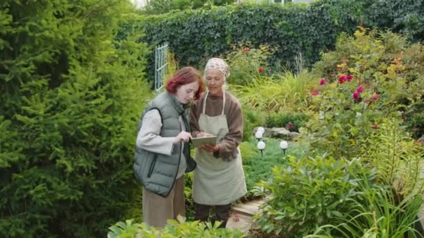 Gen Wnuczka Odwiedza Babcię Wsi Stojąc Razem Ogrodzie Ogródkowym Oglądając — Wideo stockowe