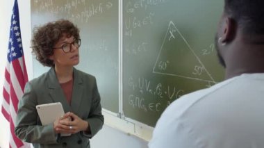 Tanımlanamayan siyahi üniversite öğrencisinin tahtada durup öğretmenine geometri problemini nasıl çözeceğini söylerken omzundan vurulması.