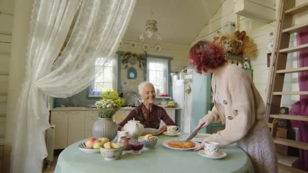 在与祖母的茶话会上 Gen Z女孩站在乡村别墅厨房的餐桌旁切馅饼 — 图库视频影像