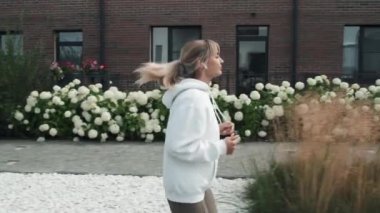 Sabahları koşarken kablosuz kulaklıkla müzik dinleyen modern genç bir kadının yan görüntüsü