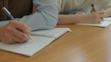 Yakın çekim, Asya 'daki genç üniversite ya da üniversite öğrencisinin gözlük takıp ders sırasında notlar alırken.