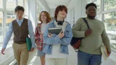 Çok ırklı Z jenerasyonundan bir grup arkadaş üniversite binaları arasında bir koridorda yürüyüp sohbet ediyorlar.