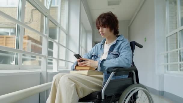 在大学走廊坐轮椅 用智能手机上网 思考某件事的时髦女性形象 — 图库视频影像