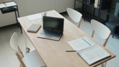 Bilgisayarları, kağıtları, kalemleri, defterleri değiştirilmiş orta boy ofis masası, etrafta üç sandalye, yukarıdan gören kimse yok.