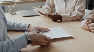 Kafkasyalı kadın başvuru formunu imzalayıp beyaz HR ile el sıkışırken genç siyahi kadın HR 'nin yanında oturması.