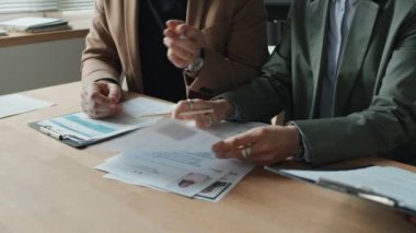 İki beyaz HR 'ın orta kesiminde, erkek ve kadın, siyah kadın HR ile birlikte CV' lere bakıyorlar, doğru adayları seçiyorlar, hepsi ofis masasında oturuyorlar.