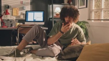 Sesini kaydeden kıvırcık bir delikanlının tam pozu ya da dirseğinin altında yastıklar, yapılmamış bir yatakta yatarken telefonla konuşması. Ekranı aç, arkaplanda lambalar ve pencere, sabahın erken saatlerinde.