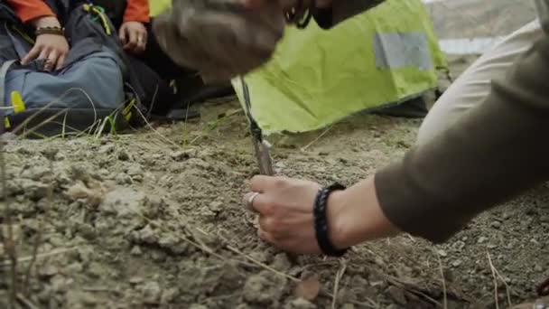 Закрытие Женских Рук Укрепляющих Столб Палатки Почву Камнем Другой Человек — стоковое видео