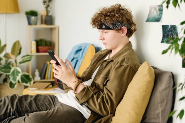 Akıllı telefonlu bir gencin yatakta oturup online video izlemesi, biriyle iletişim kurması ya da canlı yayın yapması.