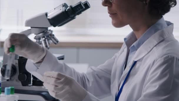 Вид Сбоку Молодой Женщины Ученого Изучающей Образцы Пробирке Через Микроскоп — стоковое видео