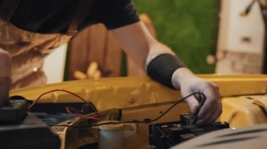 Otomobil tamircisinin açık motor kaputunun altındaki motor kablolarını denetlemesi sırasında park yerinde duran kıllı dövmeleri gevşetin.