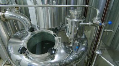 Bağımsız zanaat bira fabrikasında bira solucanlarını arıtmak için geniş paslanmaz çelik girdap fıçısının arkası. Üstünde borular ve görüş camı var.