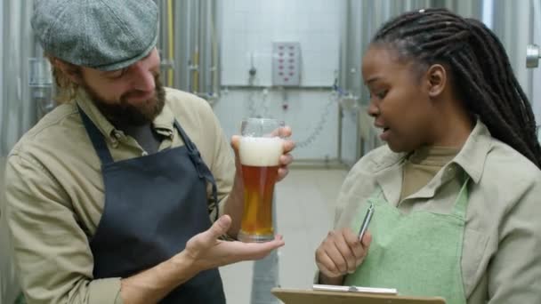Medelhög Bild Två Multietniska Bryggeriarbetare Overaller Och Förkläden Med Anteckningsblock — Stockvideo