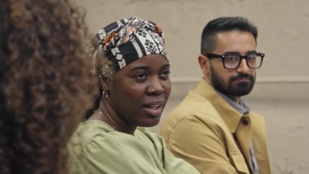 Крупный План Лица Афроамериканской Женщины Сидящей Среди Разнообразной Аудитории Митинге — стоковое видео