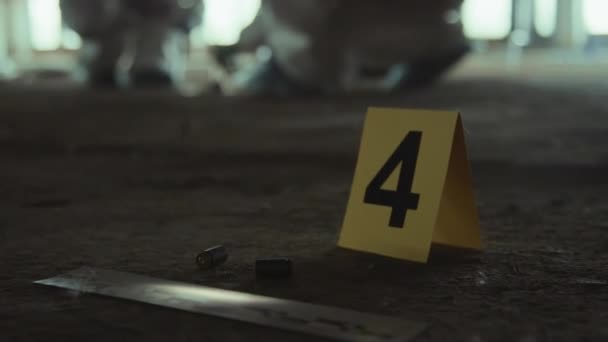 在犯罪现场近距离选择性地拍摄黄色标记 旁边有4号子弹炮弹 并在法医标尺上反射蓝色和红色闪光的警灯 — 图库视频影像
