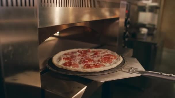 어두운 대중음식점 부엌에 헤엄을 사용하여 오븐에 익지않는 피자를 오프스크린 요리사의 — 비디오