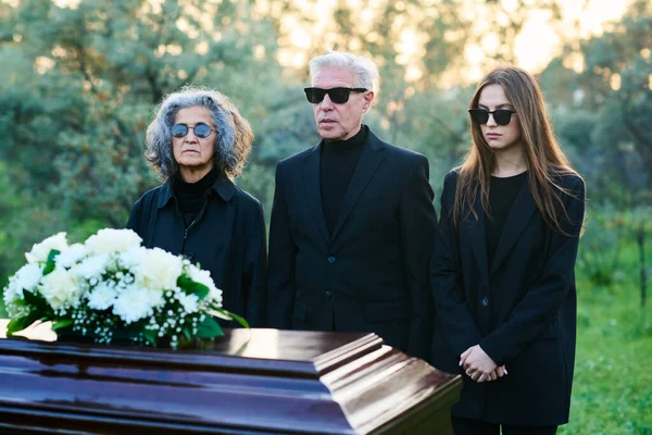 Brokenhearted Family Three Mourning Clothes Sunglasses Standing Front Closed Coffin — Stock Photo, Image
