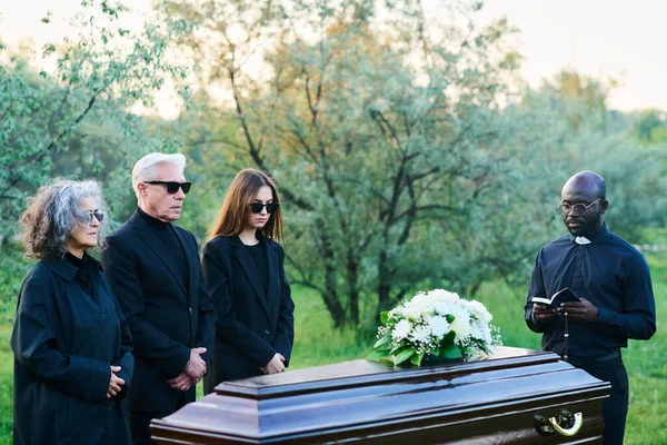 非洲裔美国牧师 身穿黑色衣服 戴着太阳镜 头戴敞篷 站在棺材旁参加葬礼 — 图库照片