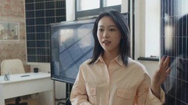Genç Çinli kadın mühendisin iş görüşmesi sırasında yenilenebilir enerji araştırma şirketinin yeni yenilikçi güneş panelinden bahsederken orta ölçekli yakın çekimi.