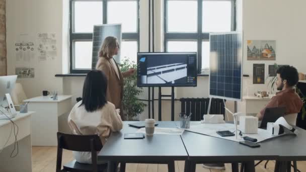 再生可能エネルギー研究会社のオフィスの注意深い同僚にマルチメディア スクリーンに太陽電池パネル プロジェクトを提示する白人男性エンジニアのフル ショット — ストック動画