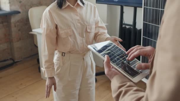 中国女工程师与白种人男性同事讨论新型太阳能电池板原型时的中等倾斜镜头 白种人正在平板电脑上查看技术图表 — 图库视频影像