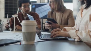 Çinli bayan meslektaşı dizüstü bilgisayarda sunum metni yazarken, çok ırklı ve Kafkas erkek mühendislerinin konut projeleri için alternatif enerji kaynaklarını tartışırken orta boy görüntüleri