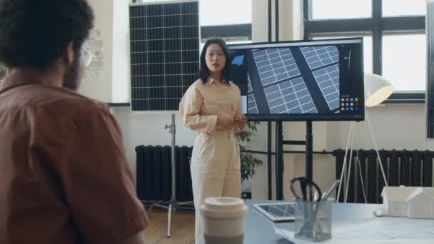中国可再生能源公司办公室多媒体屏幕上介绍太阳能电池组项目的年轻女工程师和提出问题的男同事的全面照片 — 图库视频影像