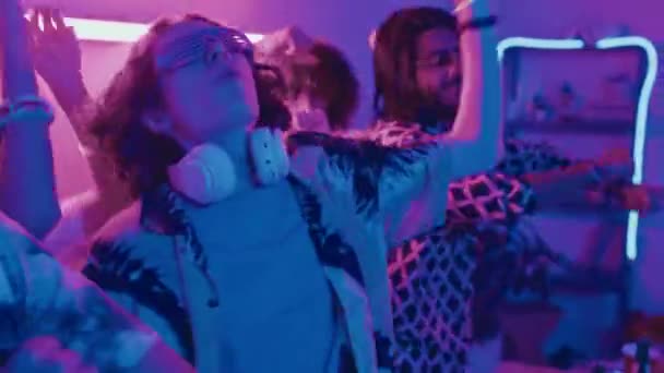 身着派对服装 穿着蓝色和粉色霓虹灯手舞足蹈 在家里欢呼雀跃的快乐青年学生的中特写镜头 — 图库视频影像