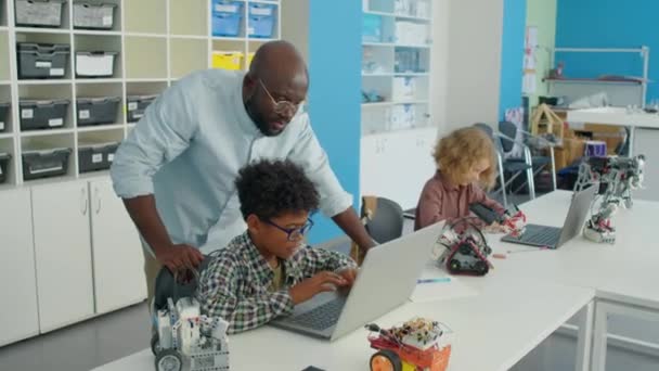Mittlere Vollaufnahme Eines Afroamerikanischen Männlichen Programmierlehrers Der Klassenzimmer Herumläuft Und — Stockvideo